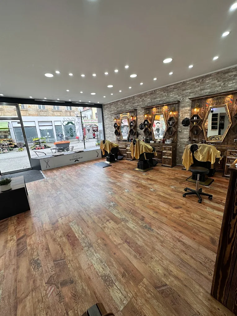 Innenraum des DLO - Barbershop mit Holzboden, Backsteinwand und Friseurst&uuml;hlen
